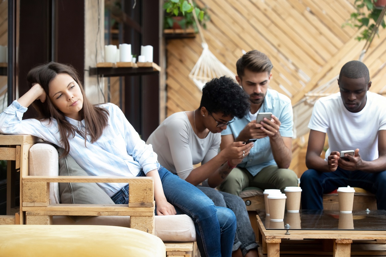 Woman alone while other people chat on phone